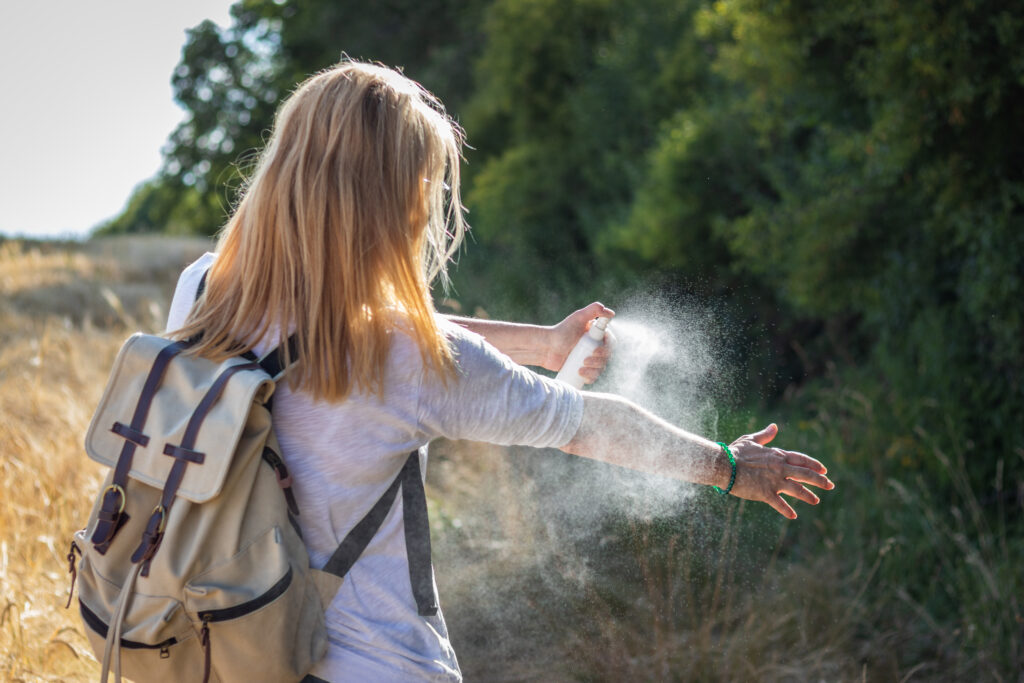 Lady spraying bug spray on herself for outdoor safety